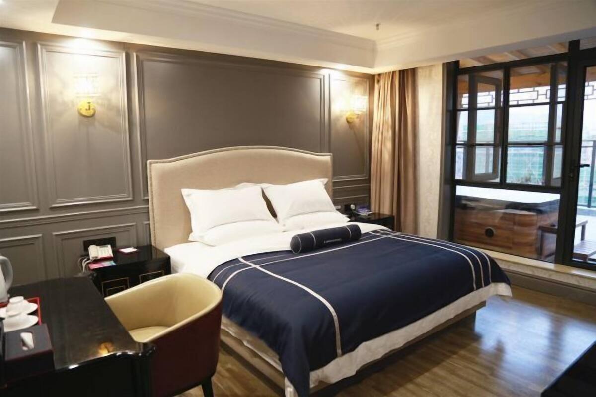 A hotel room with a large bed, bedside tables, a desk, and a chair.