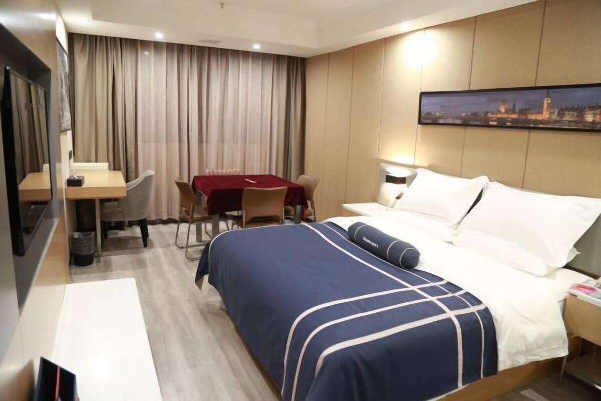 A hotel room with a bed, a desk, a chair, and a table.