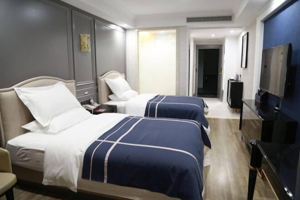 A hotel room with two beds, a TV, and a desk.