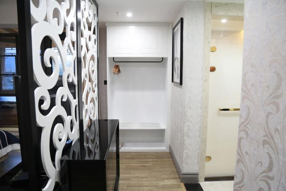 A hallway with a decorative white partition, a white cabinet, and a framed picture on the wall.