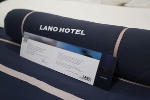 A rolled-up pillow with the text "LANO HOTEL" and a name tag. - lanyi Hotel (Guiding)