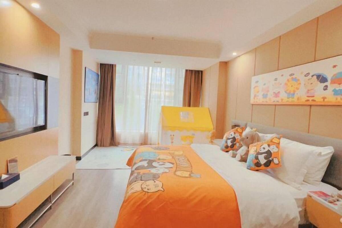 A hotel room with a bed, a TV, a desk, and a window with curtains.