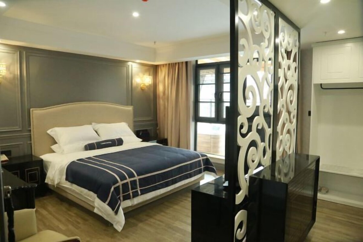 A hotel room with a large bed, a desk, and a decorative partition.