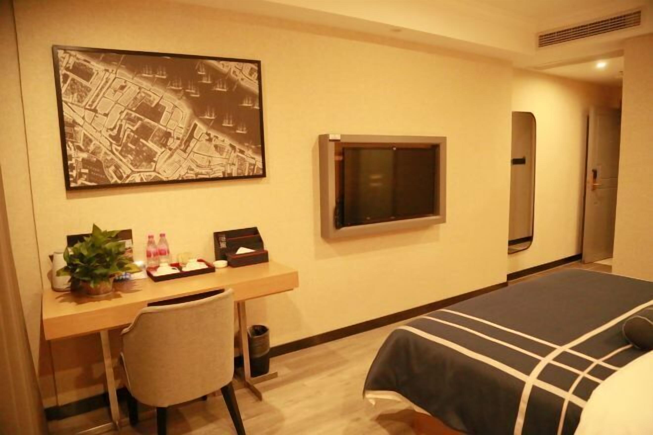 Habitación de hotel con cama, escritorio, silla y un mapa grande en la pared.
