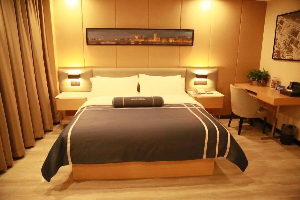 A hotel room with a large bed, two bedside tables, a desk, and a chair.