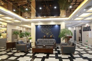 A hotel lobby with a checkered floor, seating area with sofas, a coffee table, and a decorative wall with hanging lights. - lanyi Hotel (Guiding)