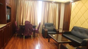 A room with a wooden floor, a television, a sofa, a table, and a chair. - Baiweilin Hotel (Cangnan)