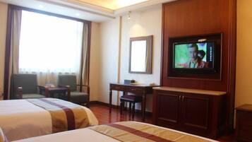 A hotel room with two beds, a television, a desk, and a chair.