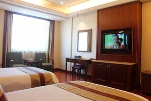 Quarto de hotel com duas camas, televisão, escrivaninha e uma cadeira.