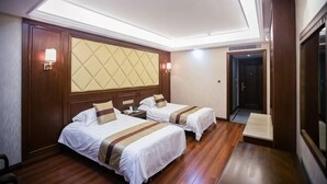 A hotel room with two beds, a large padded headboard, a wooden floor, and a door leading to a hallway. - Baiweilin Hotel (Cangnan)