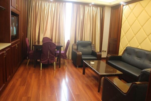 Quarto com chão de madeira, sofá, mesa e televisão.