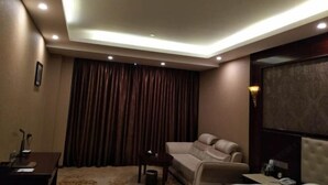 A modern living room with a sofa, a small table, and a ceiling light fixture. - Guyuecun Hotel (Yongde)