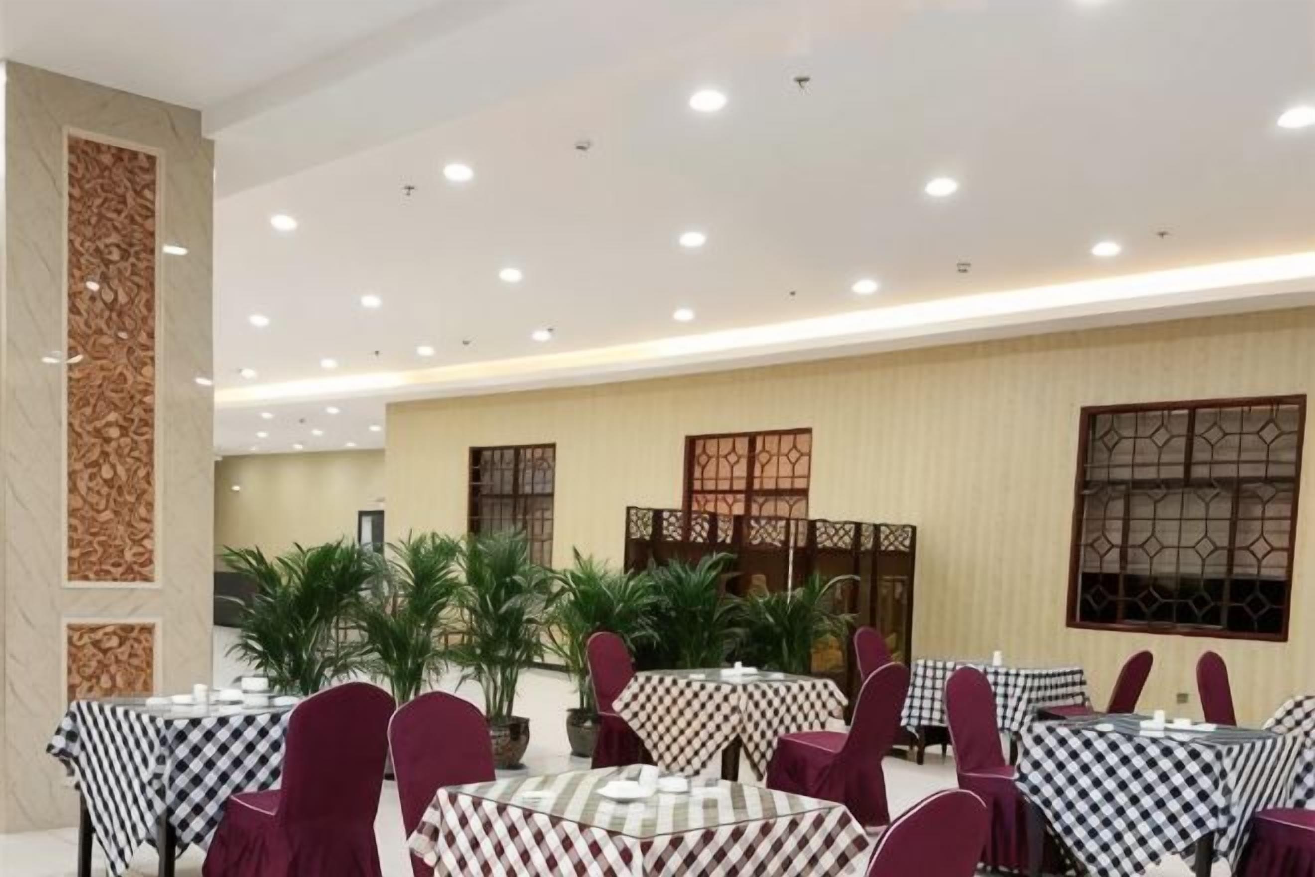 A dining area with round tables, chairs, and potted plants.