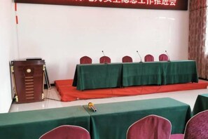 A conference room with a stage, a podium, and a table with chairs. - Guyuecun Hotel (Yongde)