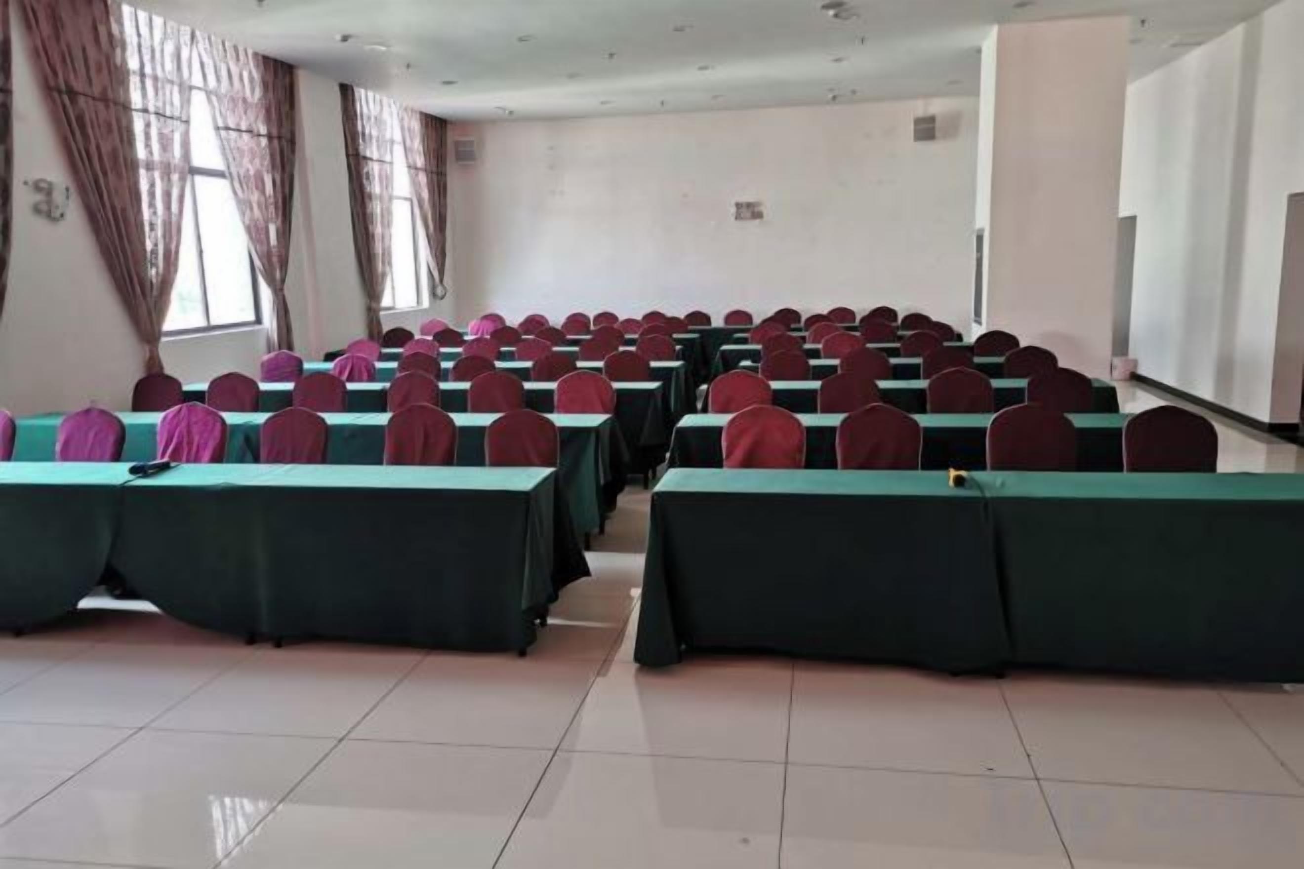 A conference room with rows of tables and chairs, large windows, and a whiteboard.
