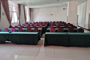 A conference room with rows of tables and chairs, large windows, and a whiteboard. - Guyuecun Hotel (Yongde)