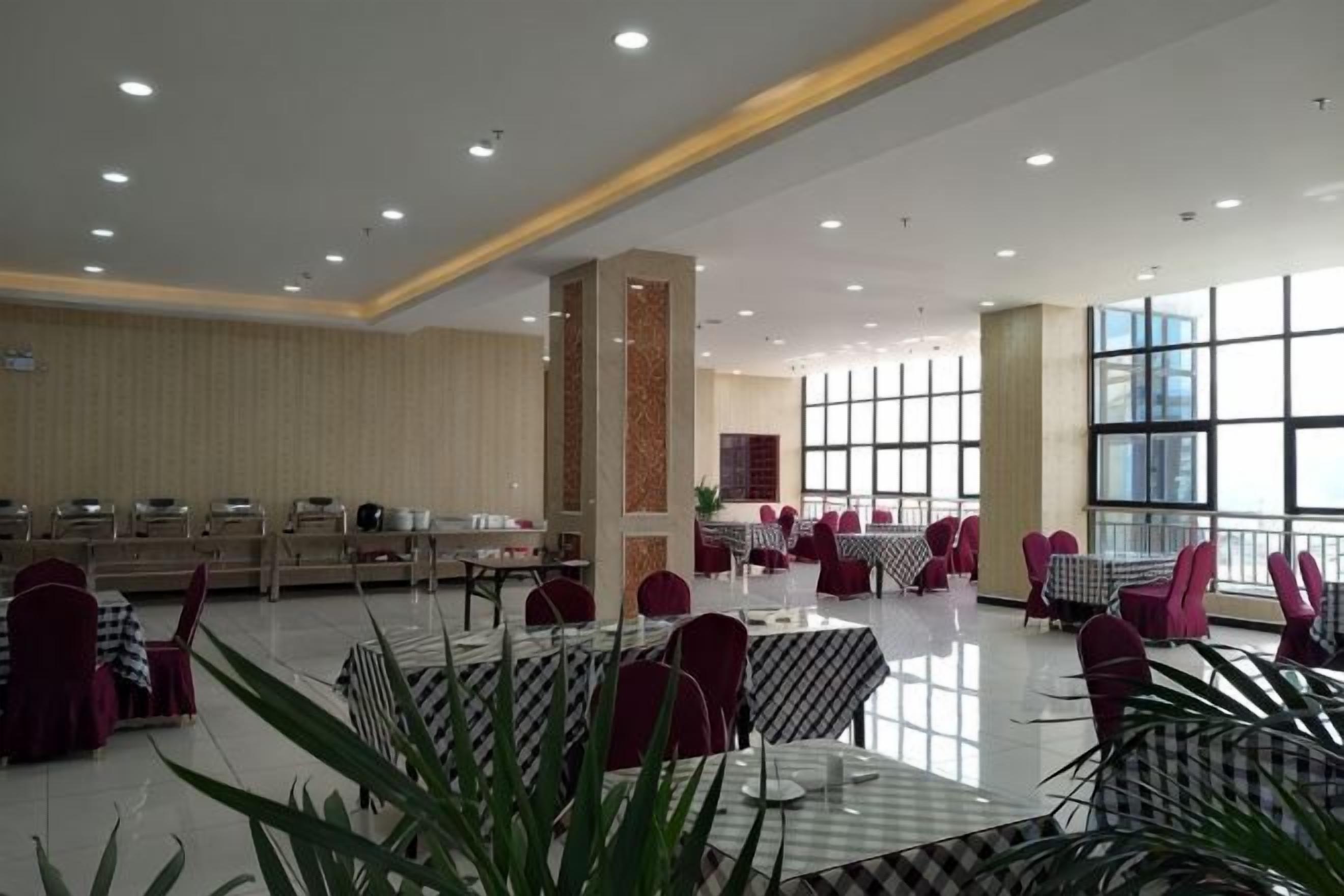 A spacious indoor dining area with multiple tables and chairs, large windows, and a high ceiling.