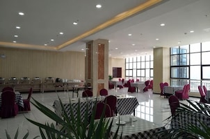 Un amplio comedor interior con varias mesas y sillas, ventanas grandes y un techo alto.