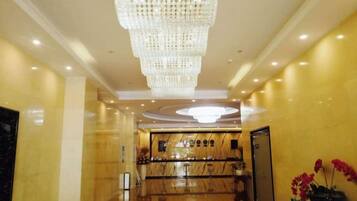 A hotel lobby with a large chandelier, a reception desk, and a polished floor.