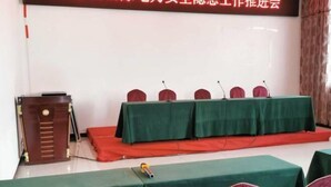 A conference room with a stage, a podium, and several chairs. - Guyuecun Hotel (Yongde)