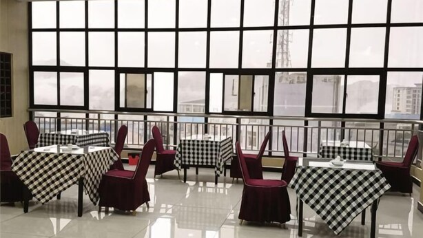 A restaurant with checkered tablecloths, red chairs, and large windows. - Guyuecun Hotel (Yongde)