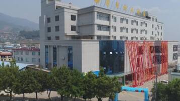 A multi-story building with a modern architectural design, featuring a prominent entrance with a glass facade and a red decorative element.