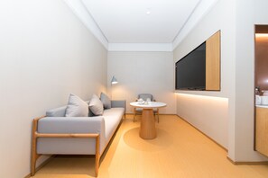 Una habitación moderna y bien iluminada con un sofá, una mesa redonda y un televisor montado en la pared.