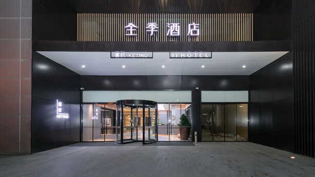 Ein Hotel mit Eingangsbereich, einer Drehtür und einem Schild mit der Aufschrift 'JI HOTEL', sowie ein Blick in die Hotelhalle.