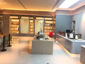 Un moderno vestíbulo de hotel con una isla central, zona de estar y una librería.