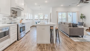 A modern kitchen with white cabinets, a central island, and a built-in oven. - Entertainment District -Walk to Stadiums - Near Six Flags -Sleeps 8 (Arlington)