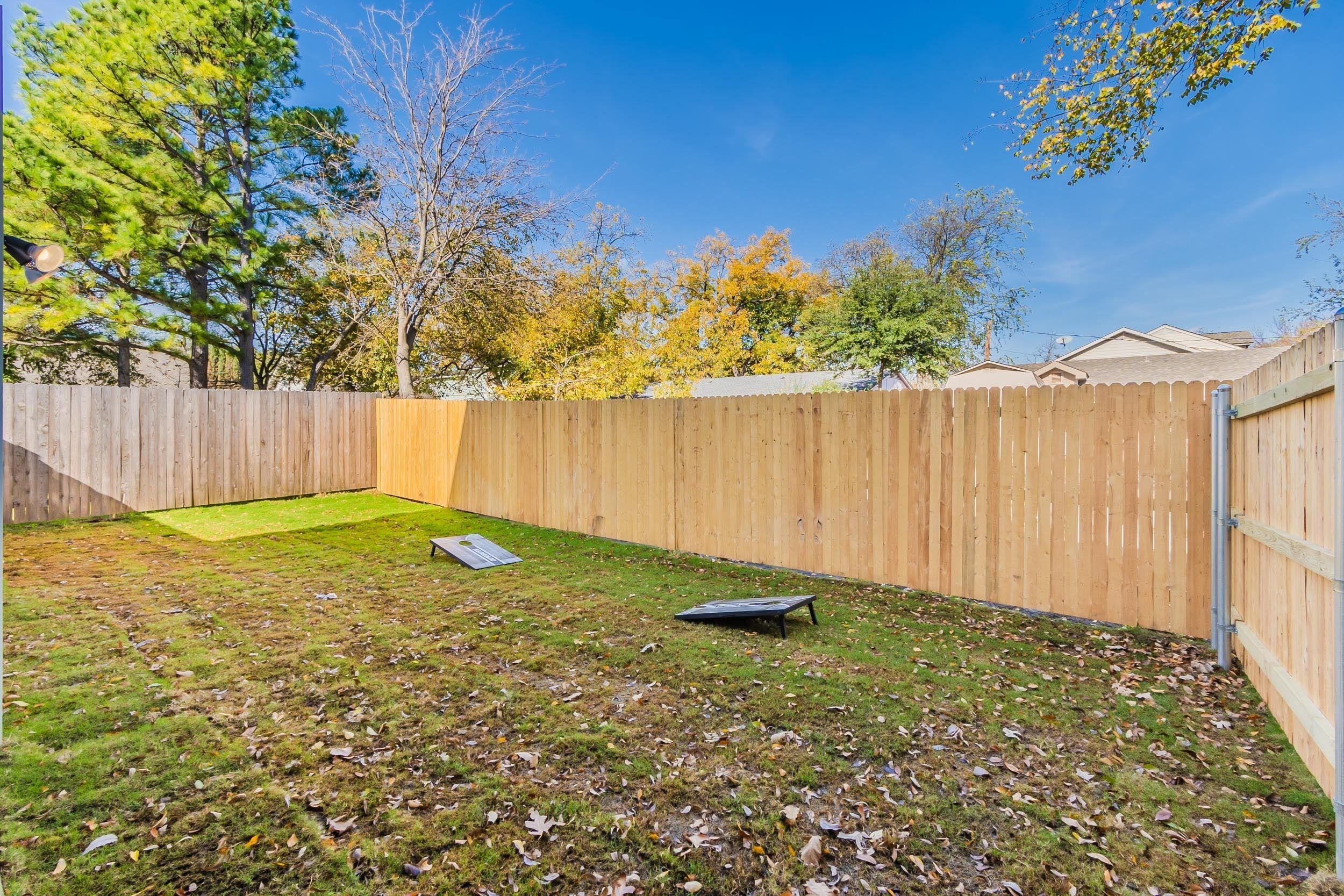 A backyard with a wooden fence, a grassy area, and trees in the background.