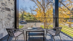 A balcony with two metal chairs and a table, overlooking a parking area and trees with autumn leaves. - Entertainment District -Walk to Stadiums - Near Six Flags -Sleeps 8 (Arlington)