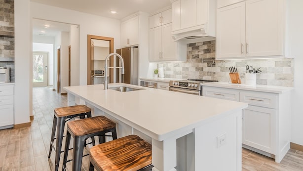 A modern kitchen with white cabinetry, a large island with stools, stainless steel appliances, and a stone backsplash. - Entertainment District -Walk to Stadiums - Near Six Flags -Sleeps 8 (Arlington)