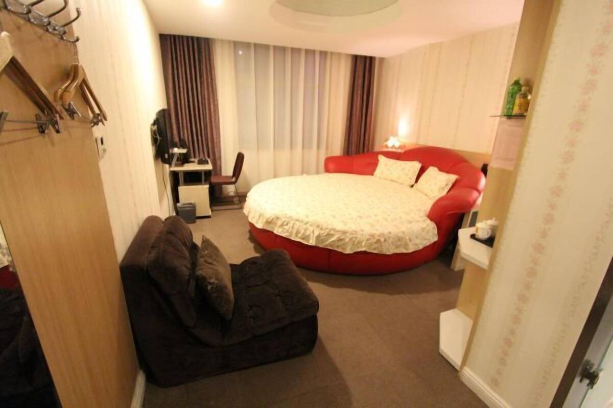 Ein Schlafzimmer mit einem roten Bett, einem kleinen Schreibtisch und einem Stuhl.
