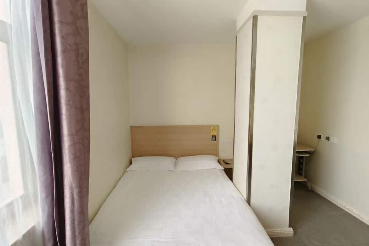 Simple, functional hotel room with a single bed and a bedside table.
