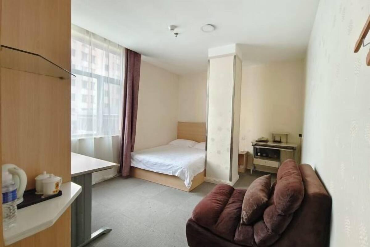 Ein Hotelzimmer mit Bett, Schreibtisch, Stuhl und einem Fenster mit Vorhängen.