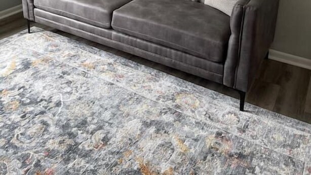 A grey tufted sofa with a neutral-toned rug and a large abstract painting on the wall. - The Mary Lou - Entire 2 Bedroom Apt in Quilt Town, USA (Hamilton)