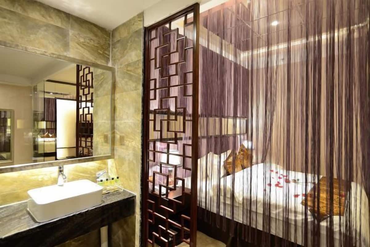 A bathroom with a marble countertop, a sink, a mirror, and a decorative partition.