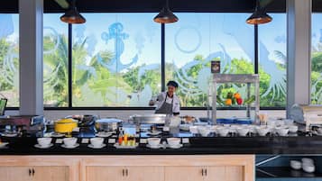 Angolo cucina con buffet, assortimento di piatti e utensili, e chef che prepara cibi.