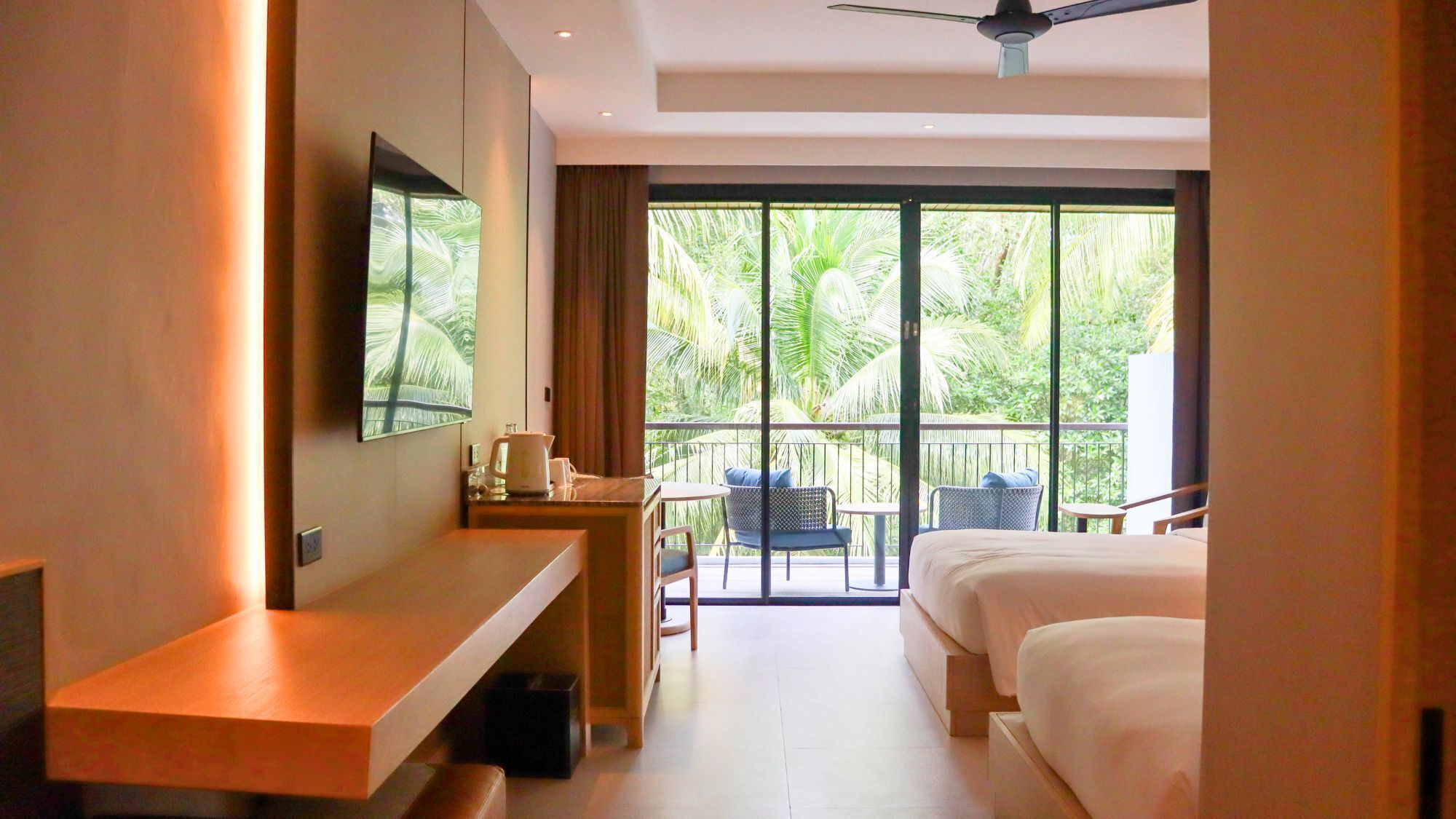A hotel room with a balcony, a desk, a bed, and a TV mounted on the wall.
