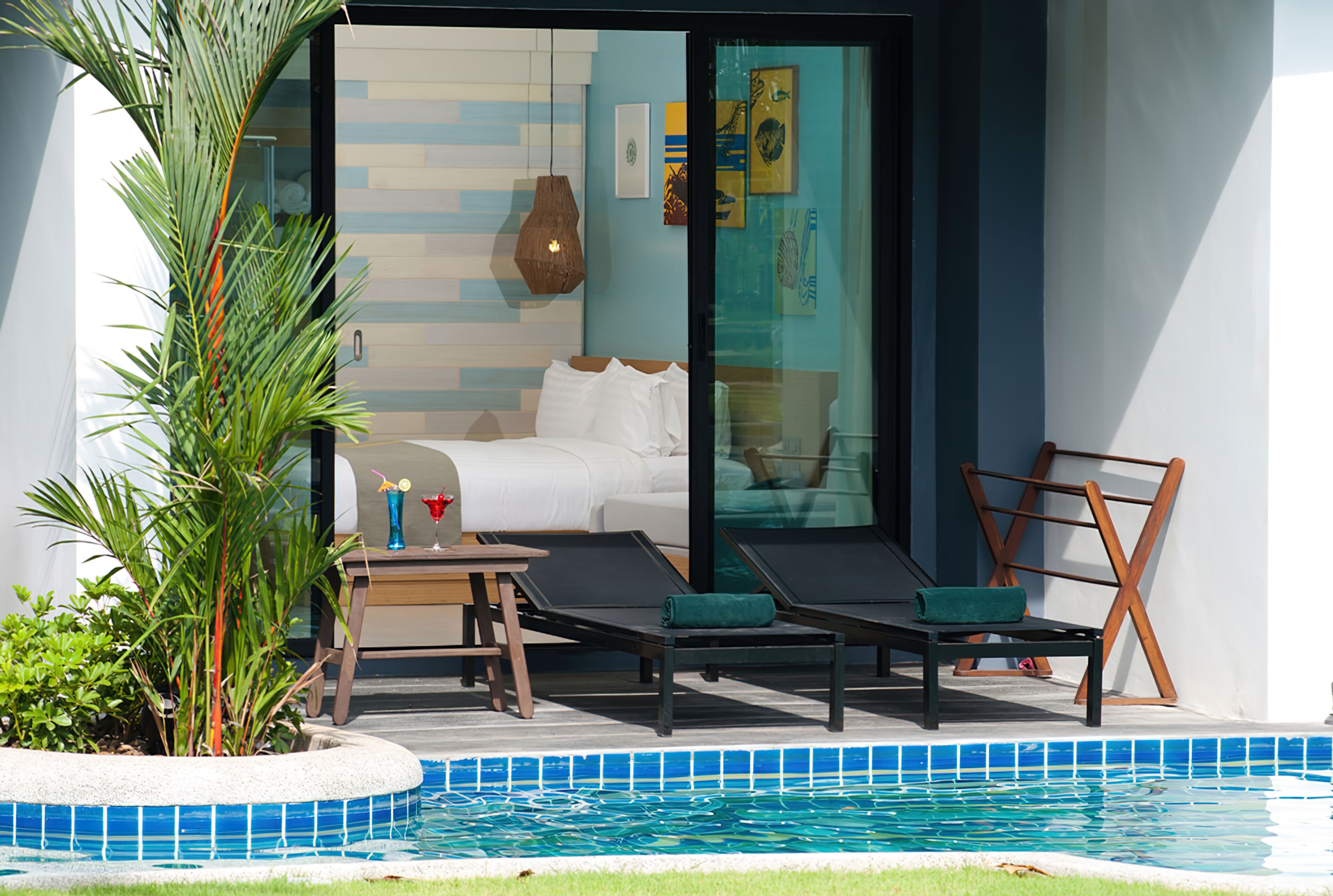 A modern hotel room with a pool, a bed, and two lounge chairs.