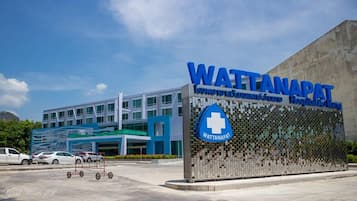 Un bâtiment moderne abritant un hôpital, avec une enseigne bien visible indiquant « Hôpital WATTANAPAT ».