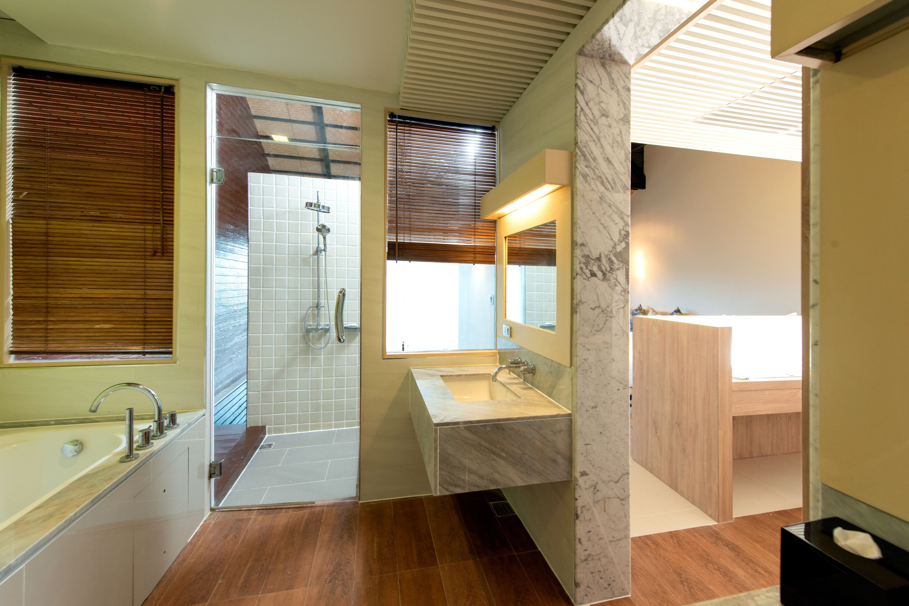 A modern bathroom with a walk-in shower, a vanity with a marble countertop, and a large mirror.