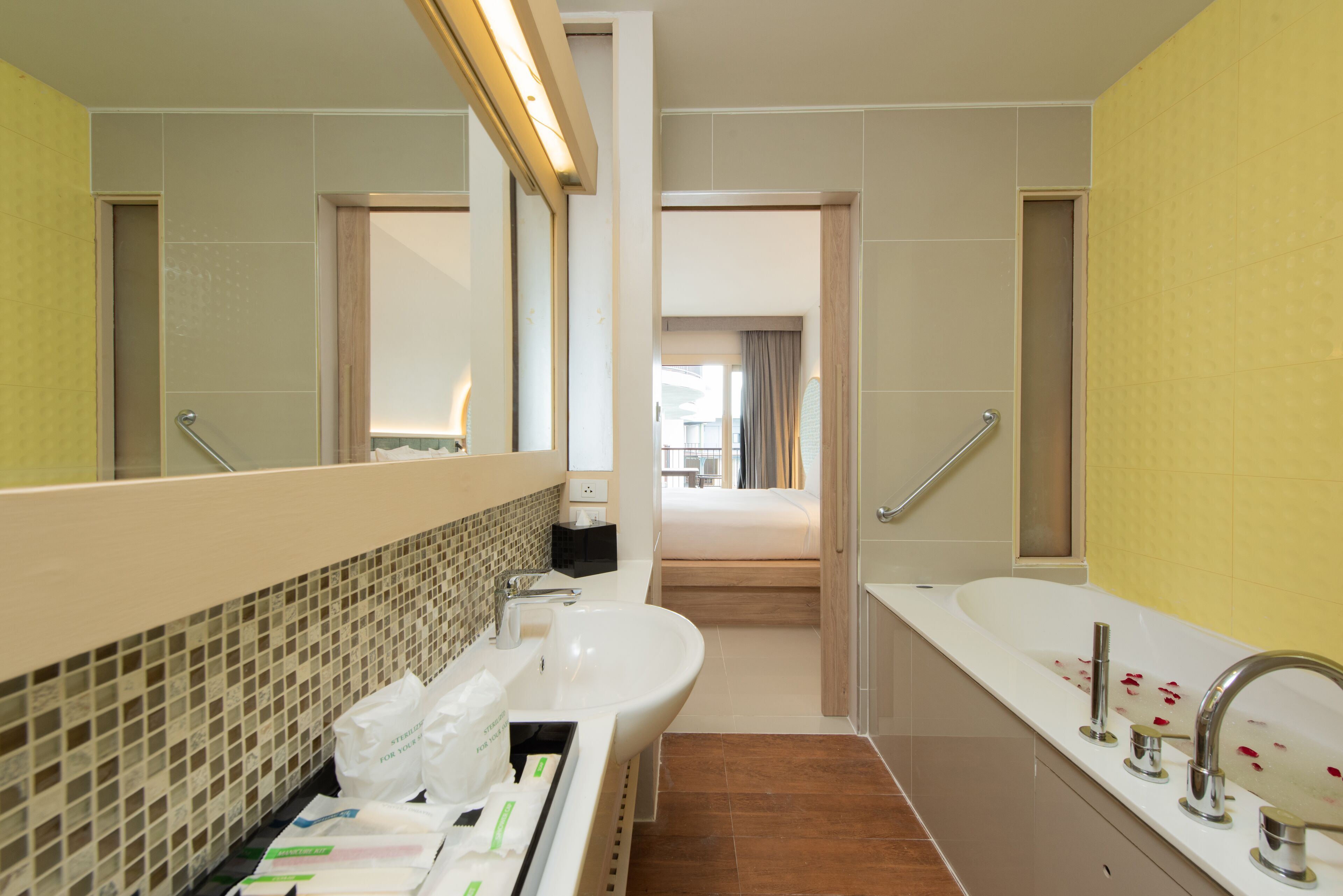 Un baño moderno con un espejo grande, un lavamanos blanco y una bañera.