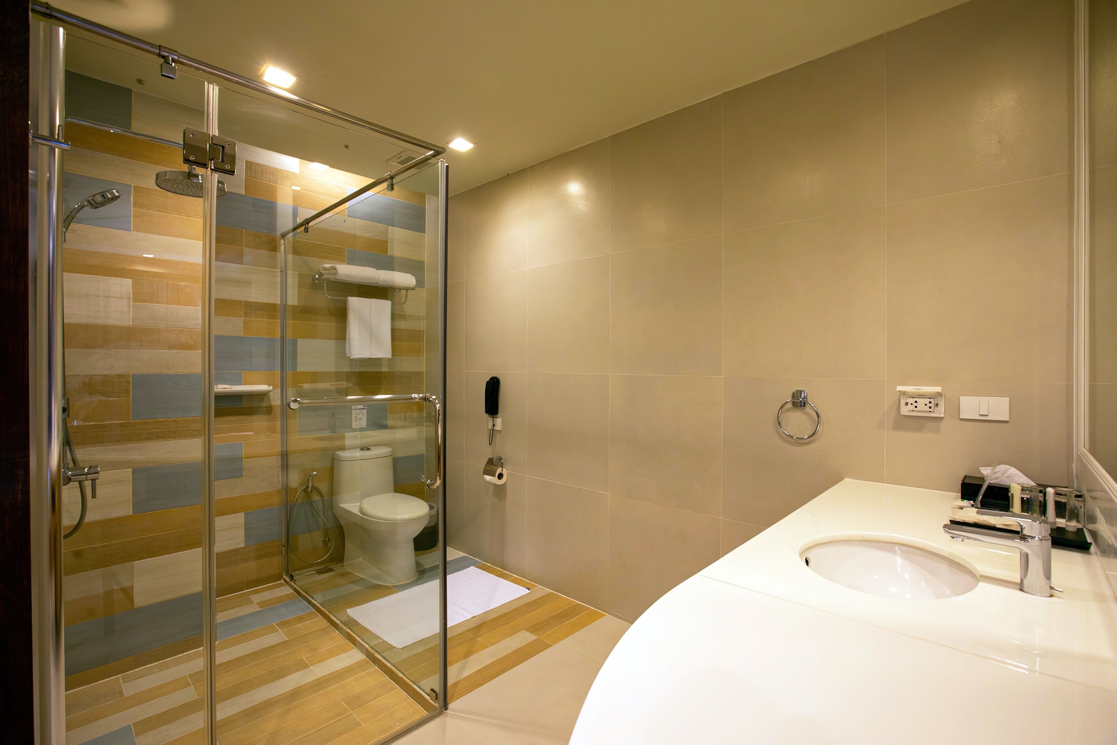 A modern bathroom with a glass-enclosed shower, a white sink, and a toilet.