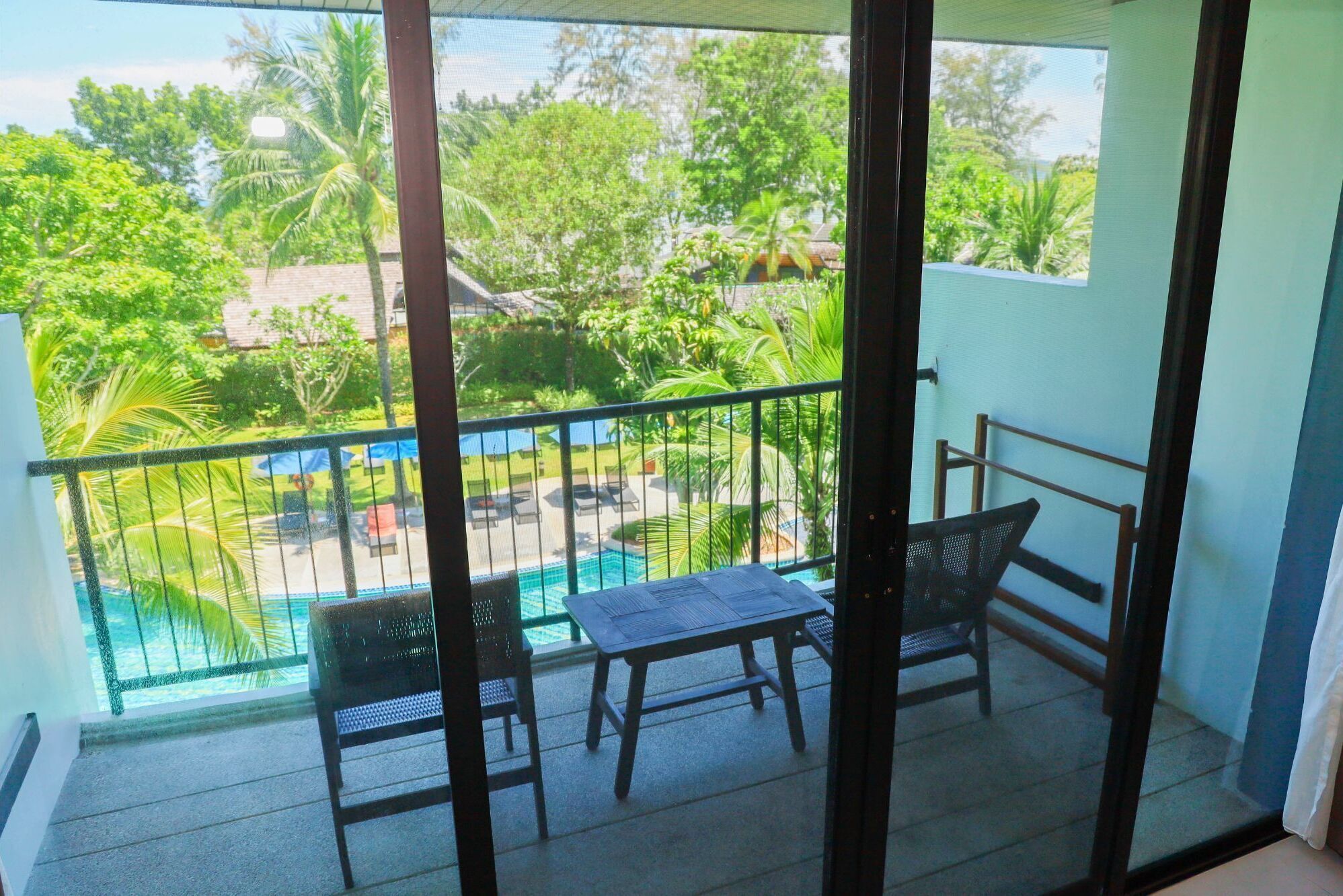 Un balcón con vistas a una piscina y abundante vegetación.