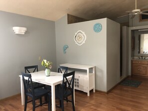 A dining area with a white table and black chairs, a vase with flowers, and a white cabinet with shelves.