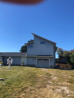A two-story house with a garage, a lawn, and a fence in the background. - Lovely apartment 5 minutes to the beach, restaurants, shopping and services  (Venice)