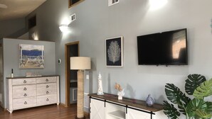 A living room with a wooden floor, a white cabinet, a lamp, a television, and a potted plant. - Lovely apartment 5 minutes to the beach, restaurants, shopping and services  (Venice)