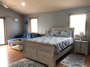 A bedroom with a wooden bed, a blue sofa, a small table, and a nightstand. There are two windows providing natural light. - Lovely apartment 5 minutes to the beach, restaurants, shopping and services  (Venice)